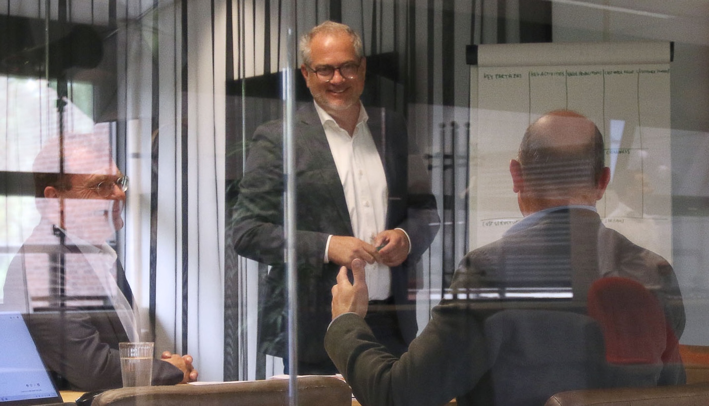 Drie mannen in business setting achter glas