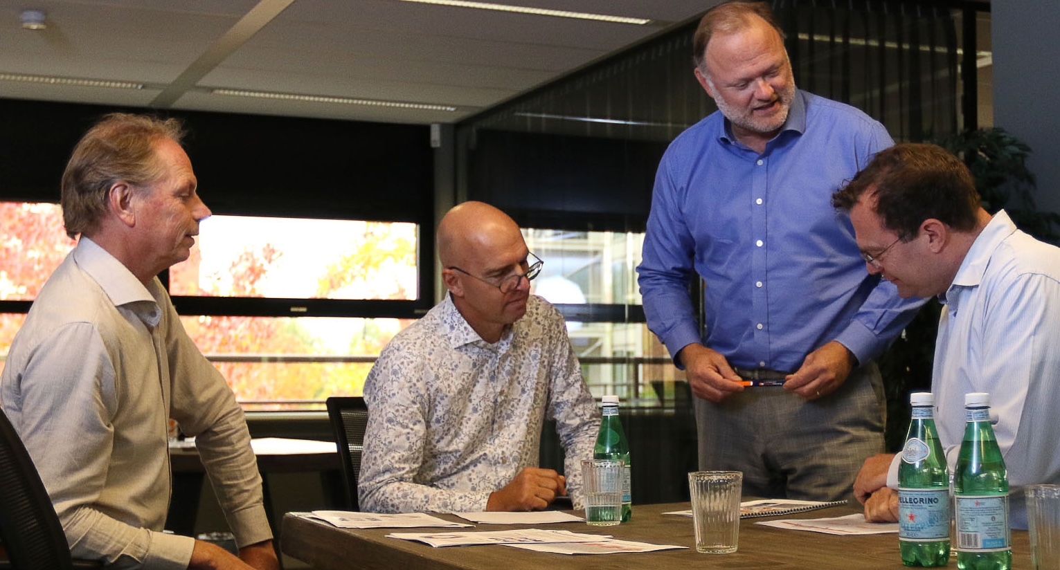 Vier mannen in overhemd in gesprek in business setting